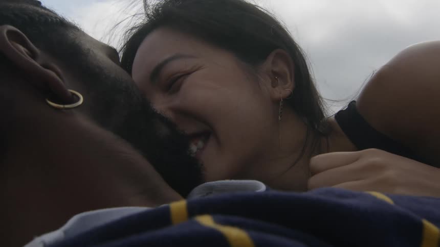 Young happy couple laying in the ground tenderly kissing while smiling