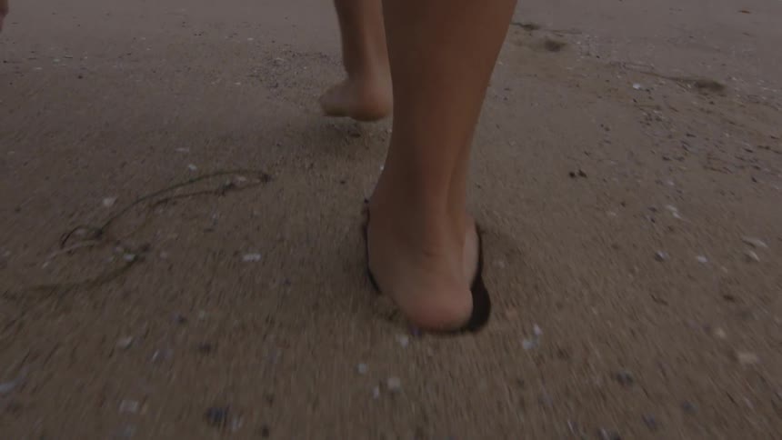 A woman walks barefoot on the beach