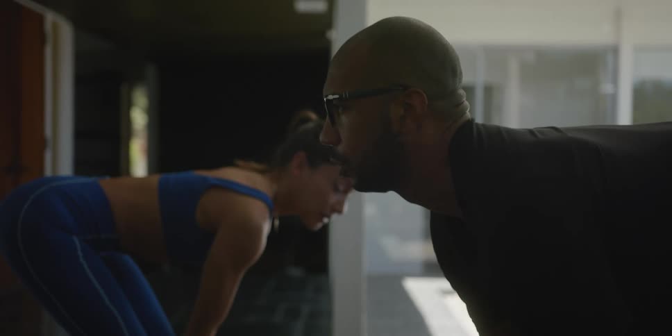 Female personal trainer guides man through weight lifting exercise in his home
