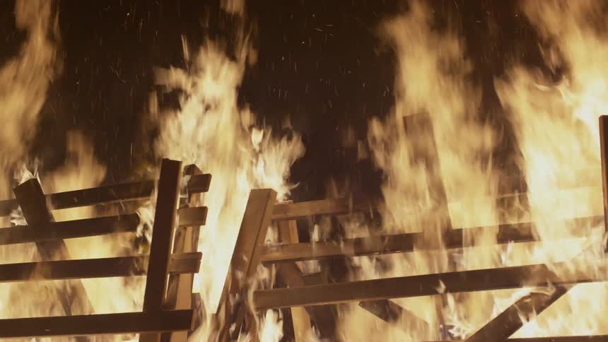 A pile of wood burns at night