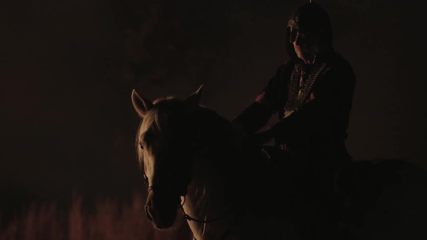 Tribal man sitting atop a horse in a dark area