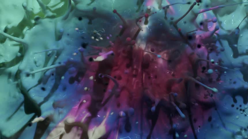 Close up of a shifting multicolored projection on a white splashing liquid sending droplets in the air