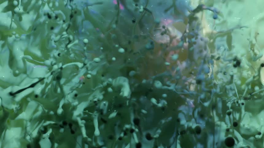 Purple and pink pastel colors reflect in a moving liquid and black and green balls float around