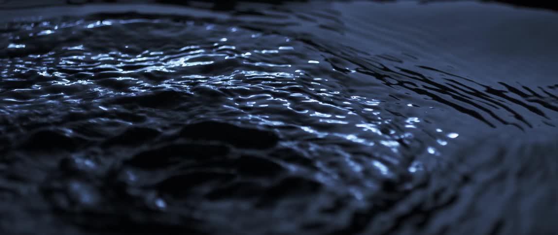 Light shines and reflects on liquid as it ripples and moves