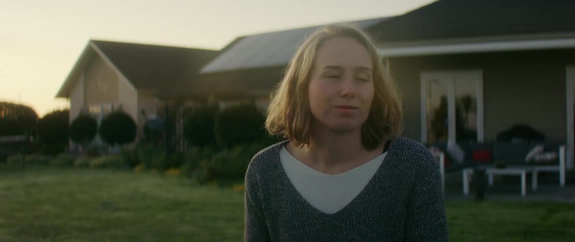Young blonde woman standing on the backyard at home at evening
