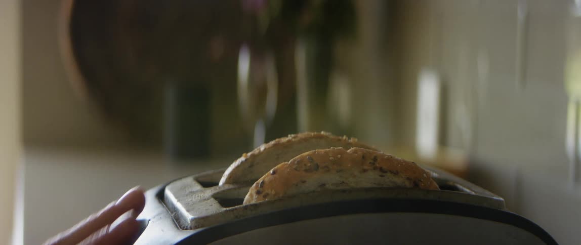 A person putting bread into a toaster