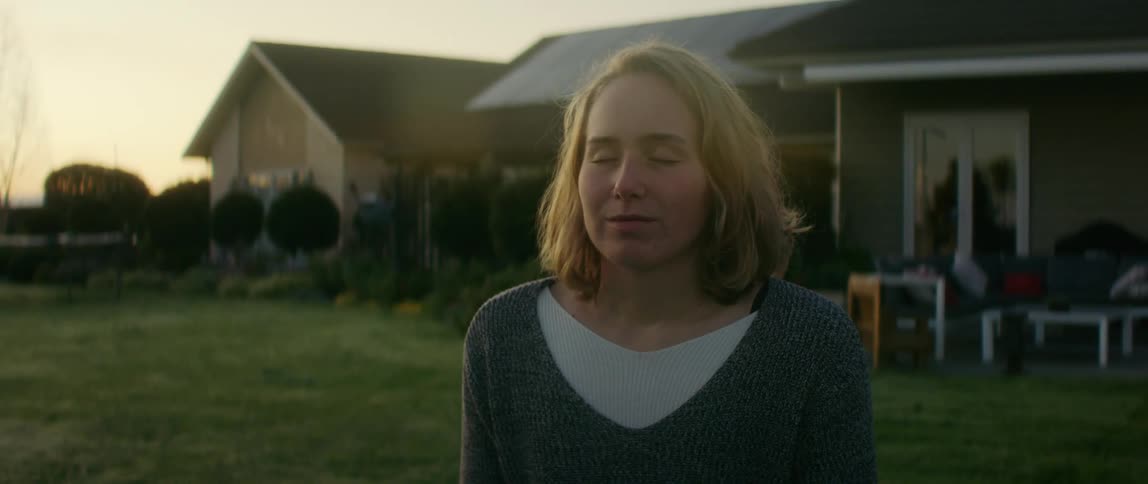 A woman is standing outdoors while the sun is setting