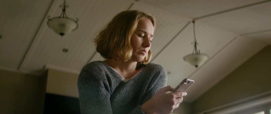 Blonde woman wearing gray sweater uses smartphone