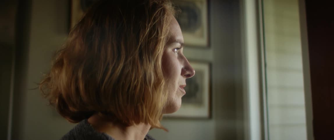Blonde female wheelchair user looks out window smiling slightly