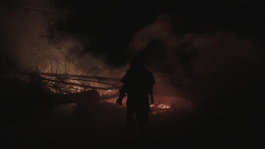 A person walks away from a fire at night