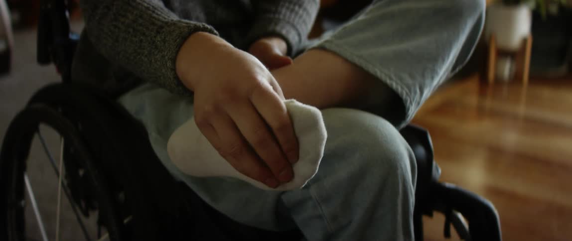 A person in a wheelchair carefully stretches their ankle