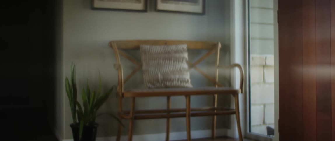 Female wheelchair user wearing gray sweater and jeans gets around in room