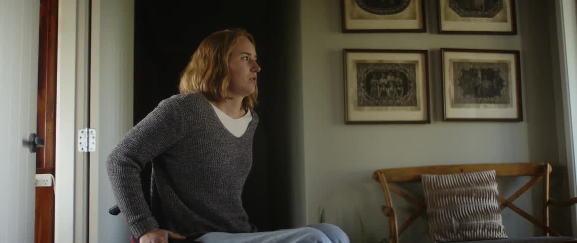 Young woman on a wheelchair gets out of a dark room into the living room