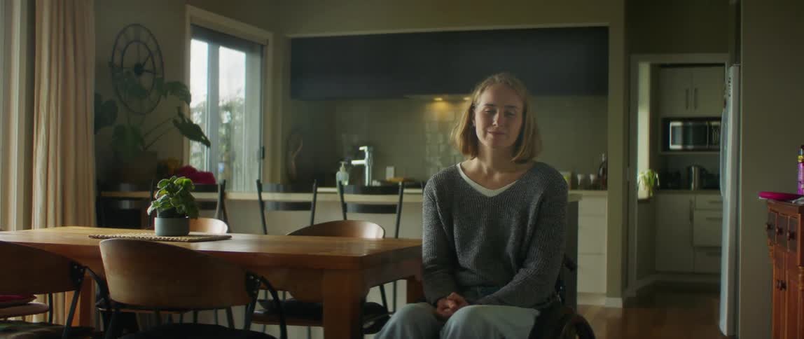 A woman sits in a wheelchair at home