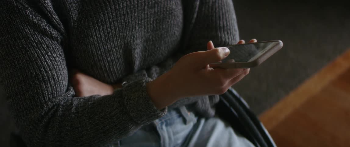 A person is sitting in a chair and texting on a cellphone