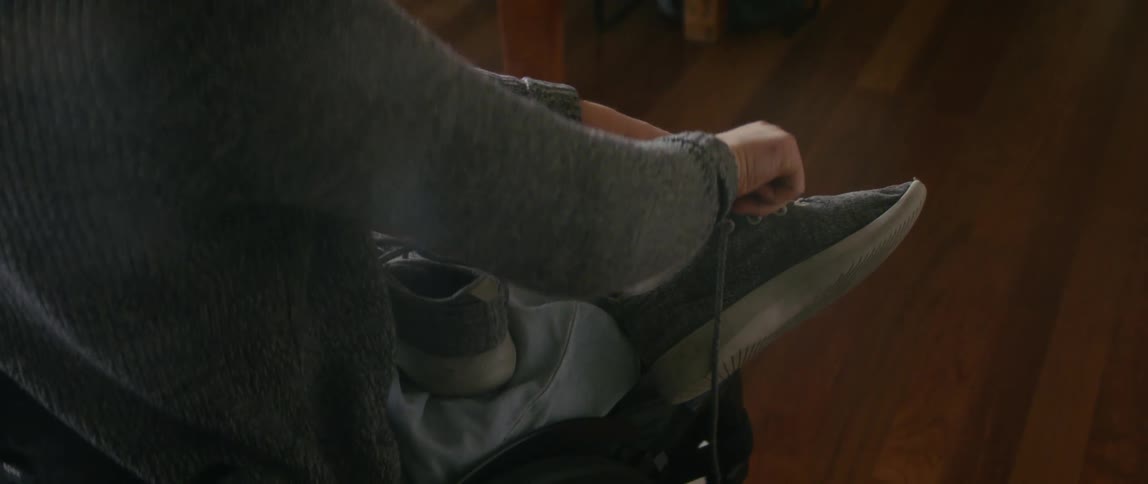 A woman in a wheel chair puts shoes on