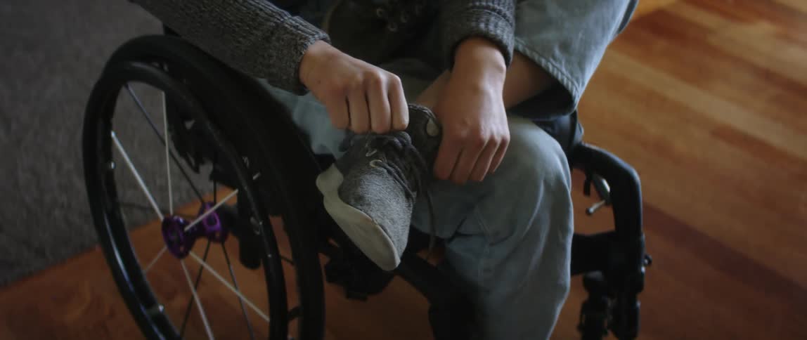 A woman in a wheelchairs puts shoes on