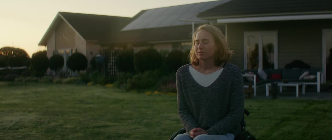 A woman sits on a chair on her front lawn