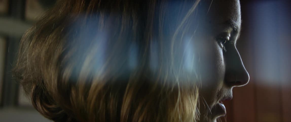 Close up of the profile of a young blonde woman sitting on the living room at home