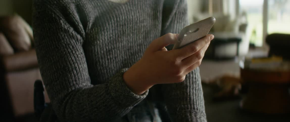 A woman is looking at her cellphone during the daytime