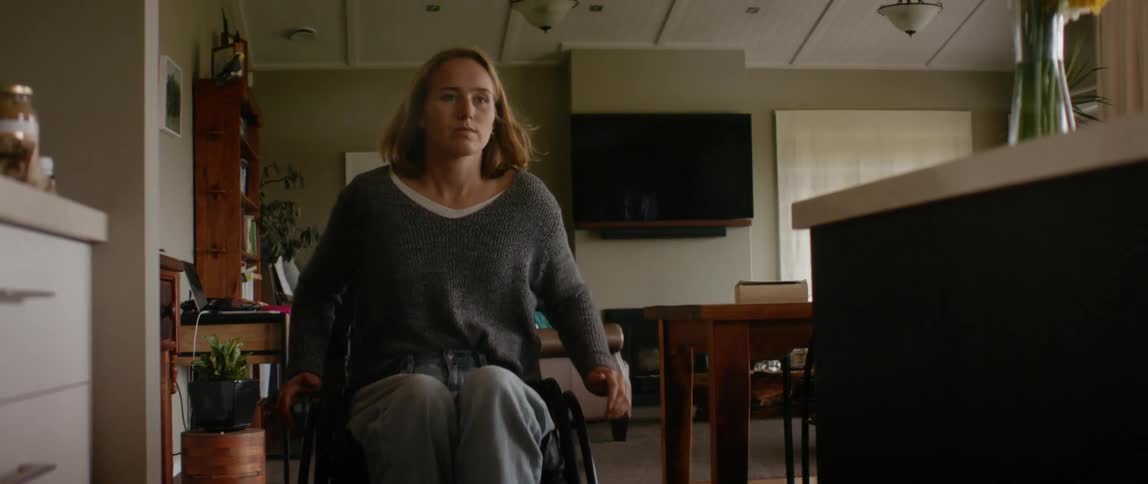 A woman wheels her wheelchair through her home