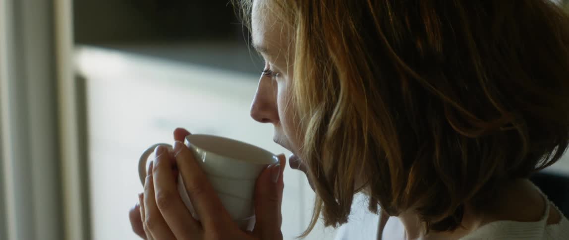 Young woman drinks a hot beverage at home