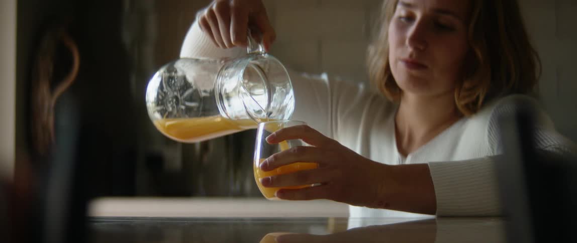 A woman is pouring a glass of juice