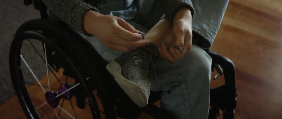 A person is sitting in a wheel chair and tying their shoe
