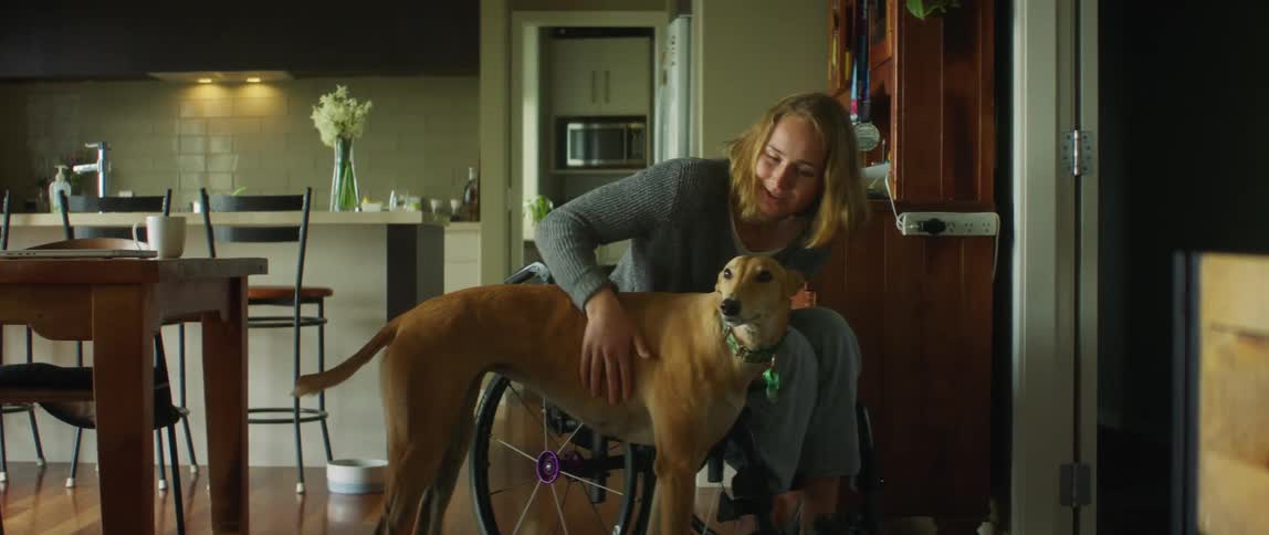 A woman is sitting down and petting her dog
