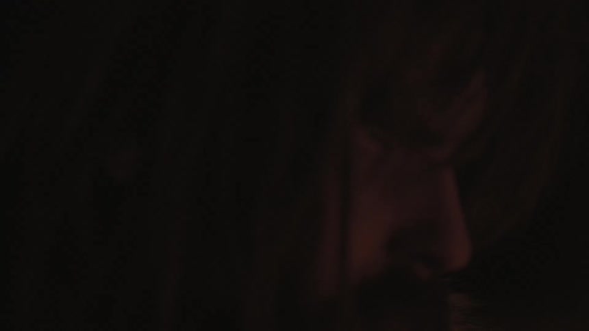 A man sits staring at a campfire