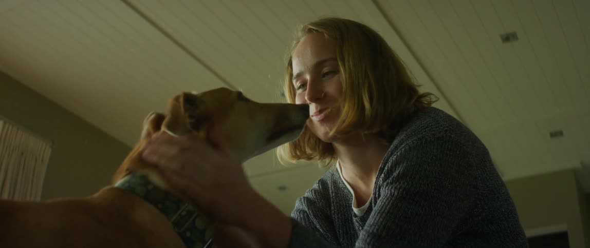 Woman sitting at home smiles while petting dog
