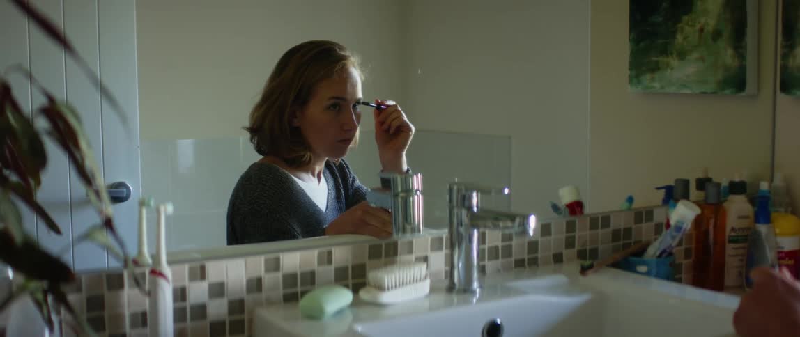 A woman is in the bathroom and applying makeup