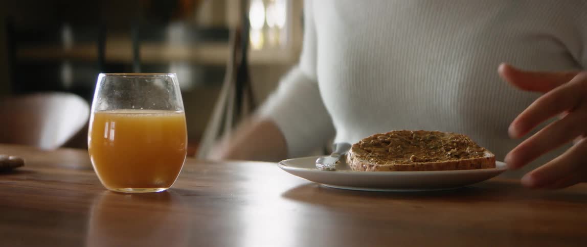 Wheelchair user wearing a white sweater has breakfast in the kitchen