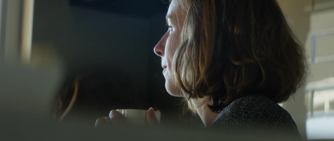 A woman is sitting down and drinking a cup of coffee