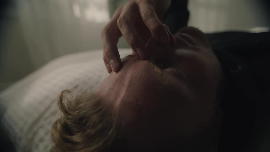A man rubbing his forehead while lying in bed