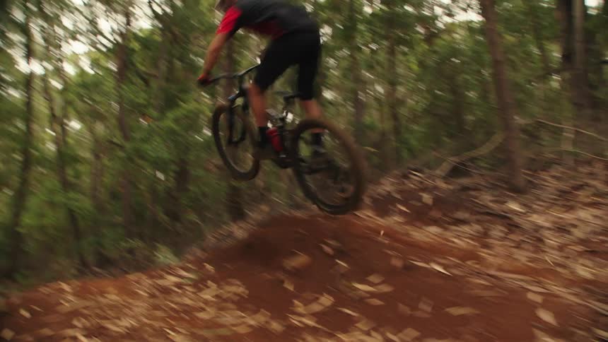 A man going off a dirt ramp jump on a mountain bike