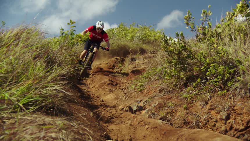 A man speeding down a dirt hillside on a mountain bike