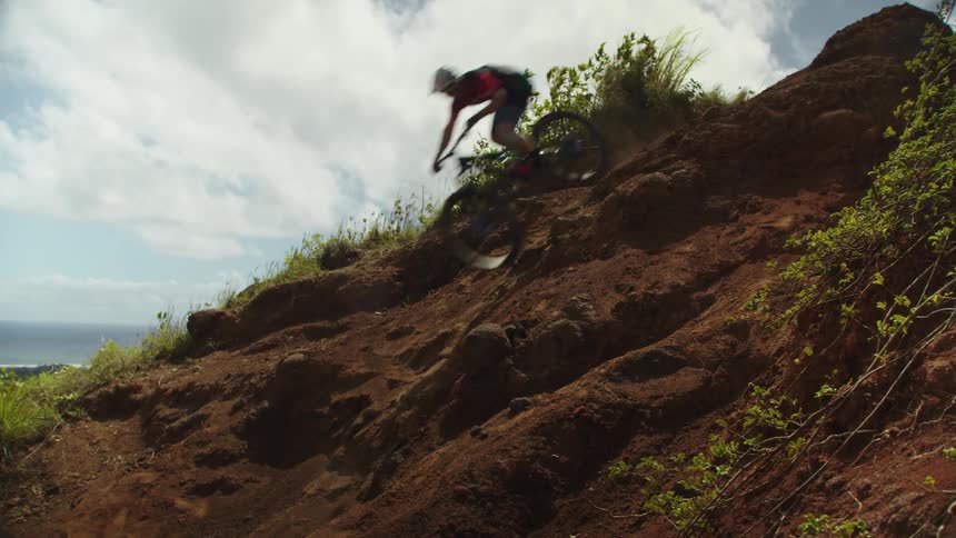 A mountain biker speeding down a dusty hillside