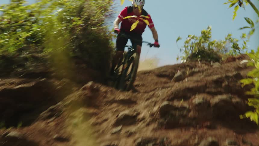 A man speeding down a rocky hillside on a mountain bike
