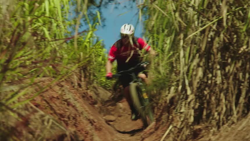A teenage boy on a bike rides wild a dirt trail in the woods