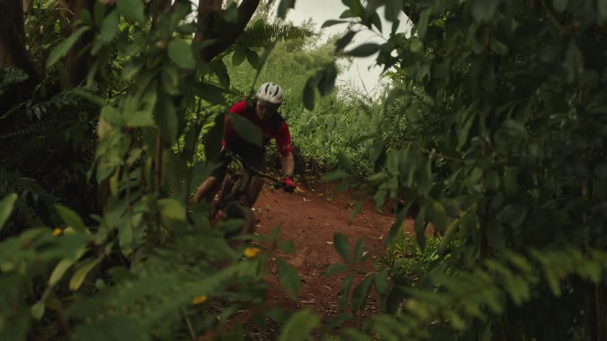 A man is riding a dirt bike through a forest