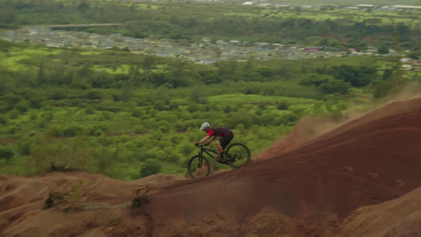 A cyclist rides a bicycle offroad down a craggy mountain slope in the countryside on a cloudy day