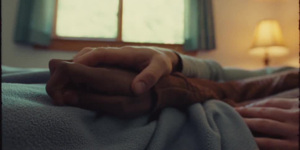 Two people are laying down and holding hands