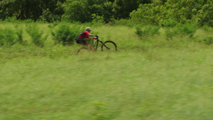 A man is riding his bike through a field