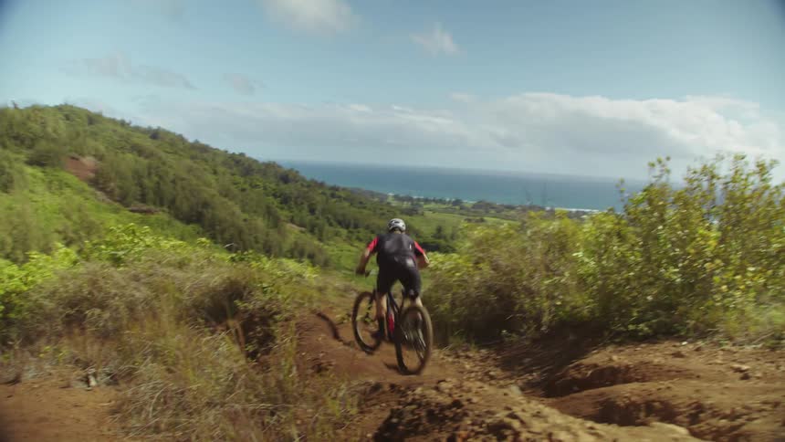 A cyclist rides down dirt hills in the countryside