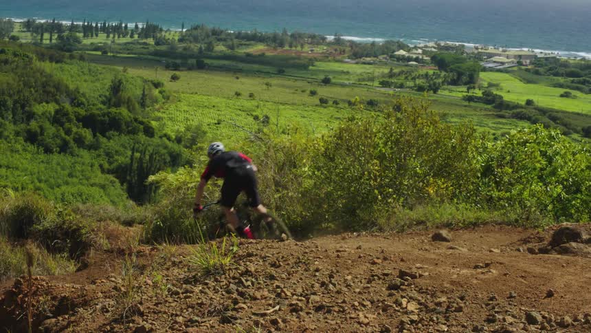 A man is riding a dirt bike through a rural area