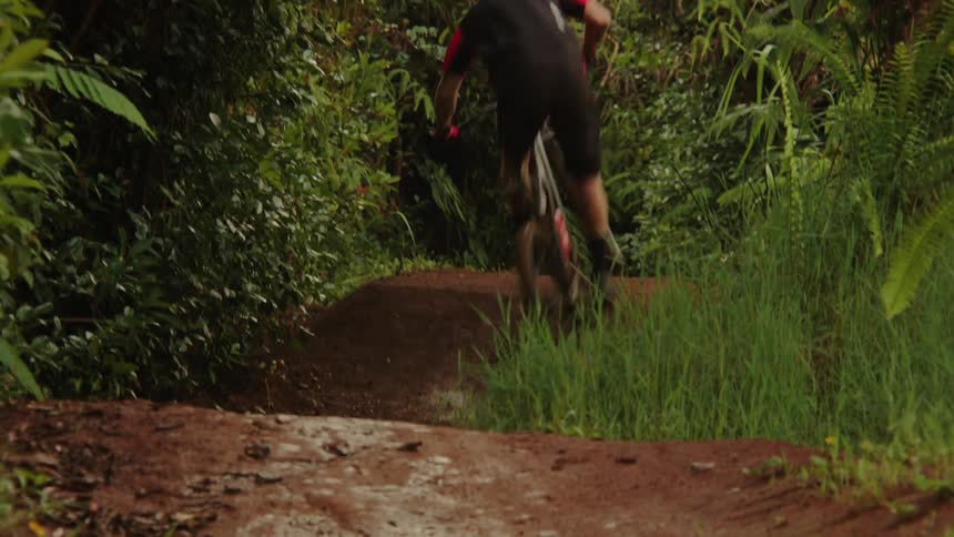 A man going over a dirt jump on a mountain bike