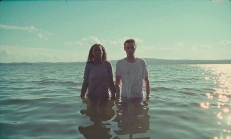 Young man and woman wearing casual clothing standing in the middle of a lake side by side during daytime