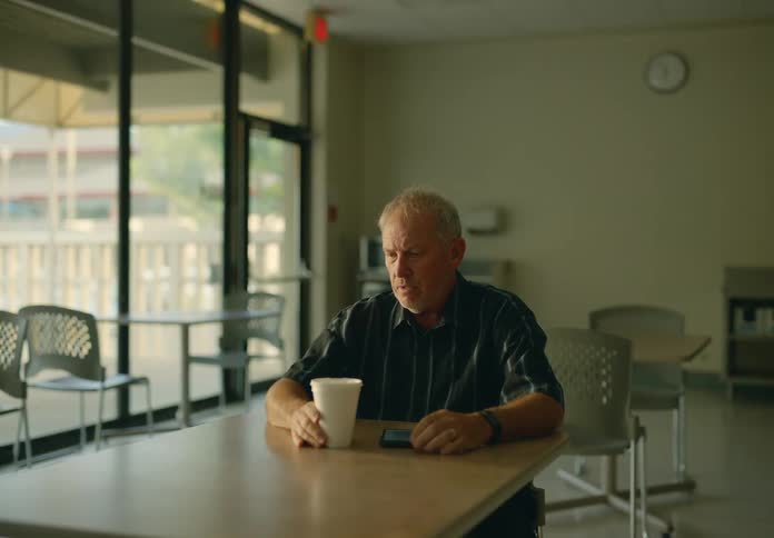 A man sits with a drink in a cafeteria