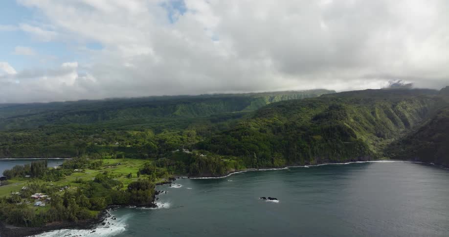 A boat sails off the coast of an island